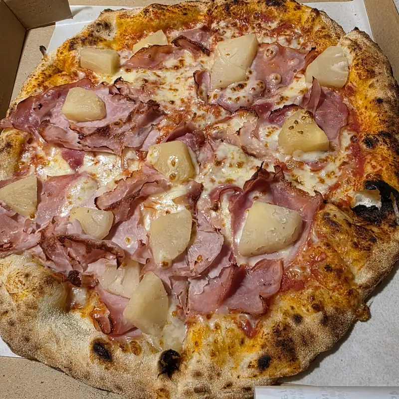 Pizza z szynką i ananasem w pudełku na wynos