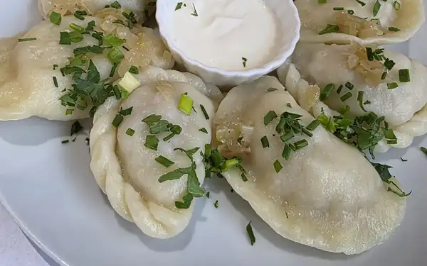 Pierogi z sosem na białym talerzu w kratkę